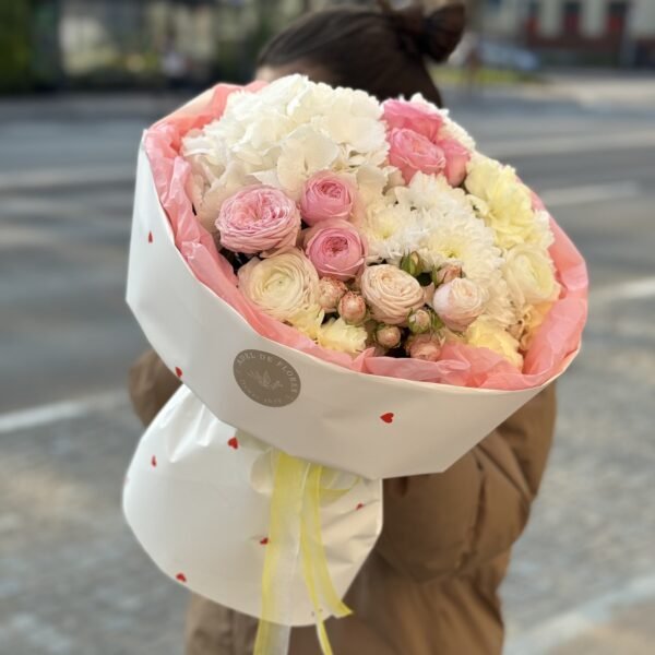 A bouquet of white hydrangeas, roses and buttercups