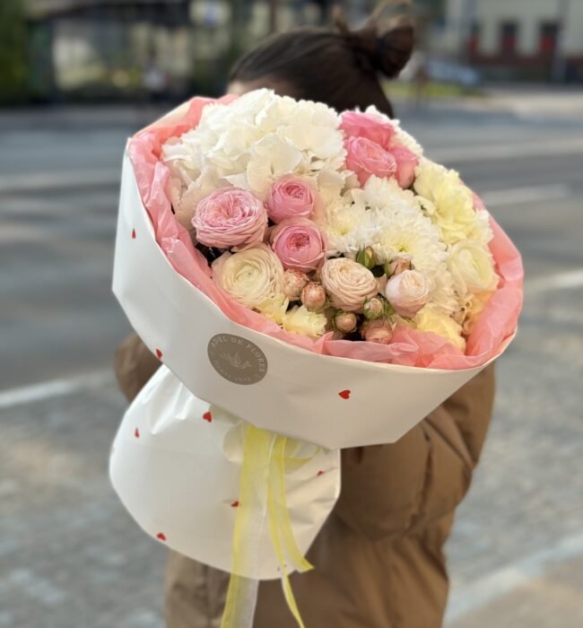 A bouquet of white hydrangeas, roses and buttercups