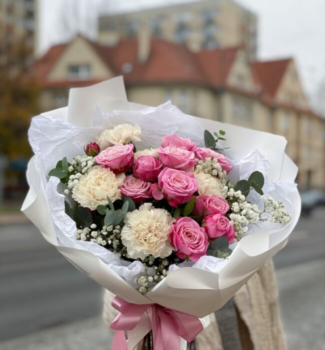 A bouquet of pink roses, cream-coloured carnations and gypsophila